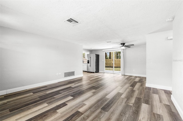 unfurnished living room with visible vents, a textured ceiling, and wood finished floors