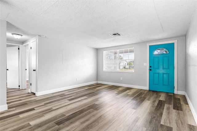 foyer featuring a textured ceiling, wood finished floors, visible vents, and baseboards