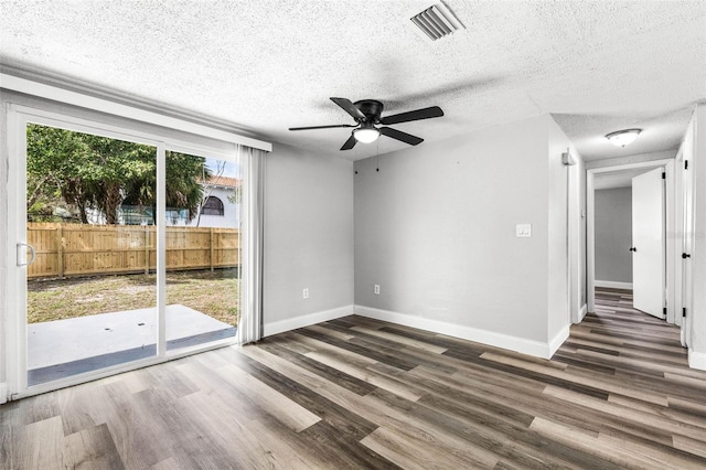 spare room with a textured ceiling, wood finished floors, visible vents, and baseboards