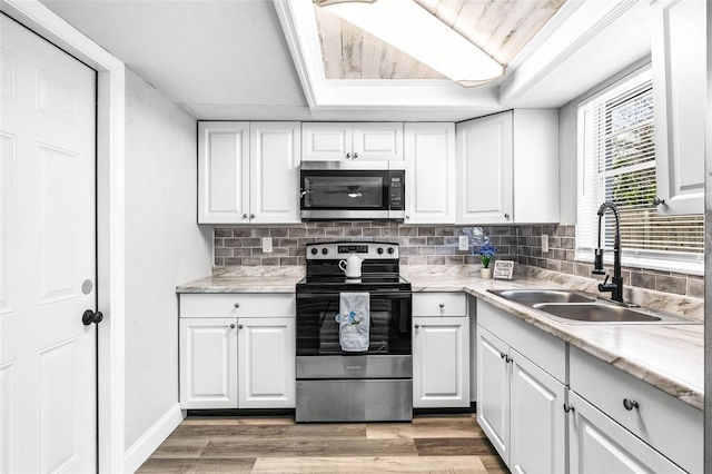 kitchen featuring appliances with stainless steel finishes, light wood-type flooring, white cabinets, and a sink