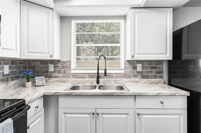 kitchen with light countertops, white cabinets, a sink, and backsplash