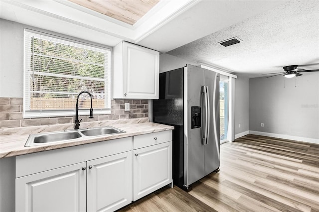 kitchen with a sink, visible vents, stainless steel fridge with ice dispenser, light wood-type flooring, and decorative backsplash