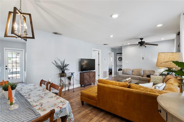 living room with recessed lighting, visible vents, stacked washing maching and dryer, wood finished floors, and baseboards