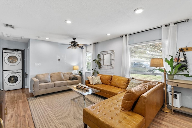 living area with stacked washer and dryer, light wood-type flooring, visible vents, and recessed lighting