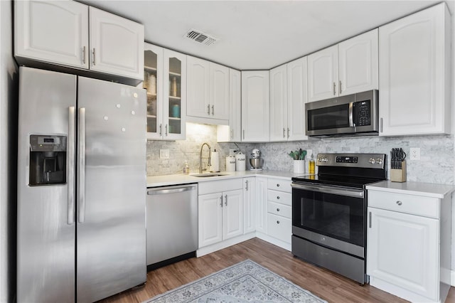 kitchen with visible vents, dark wood-style floors, glass insert cabinets, stainless steel appliances, and a sink