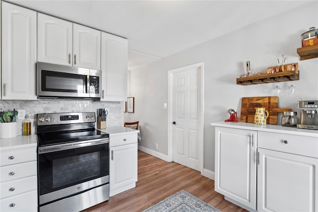 kitchen with light wood finished floors, tasteful backsplash, appliances with stainless steel finishes, light countertops, and white cabinetry