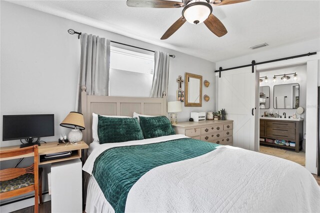 bedroom featuring a ceiling fan, visible vents, ensuite bath, and a barn door