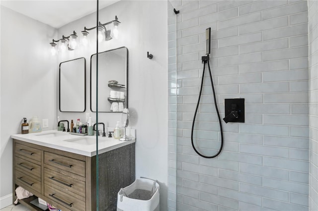 full bath with double vanity, a sink, and tiled shower