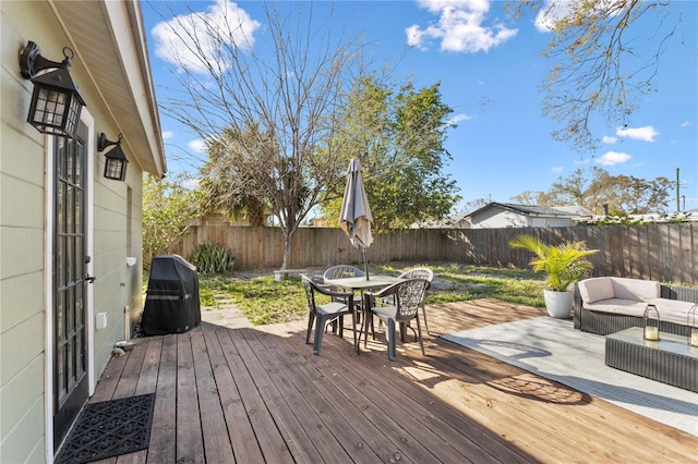 wooden deck featuring outdoor dining area, a fenced backyard, and grilling area