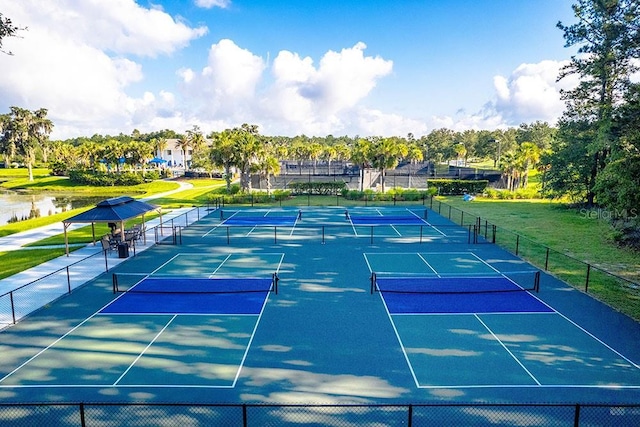 view of tennis court featuring a water view and fence