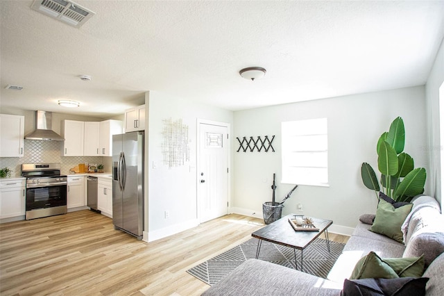 living room with light wood-type flooring, visible vents, and a textured ceiling