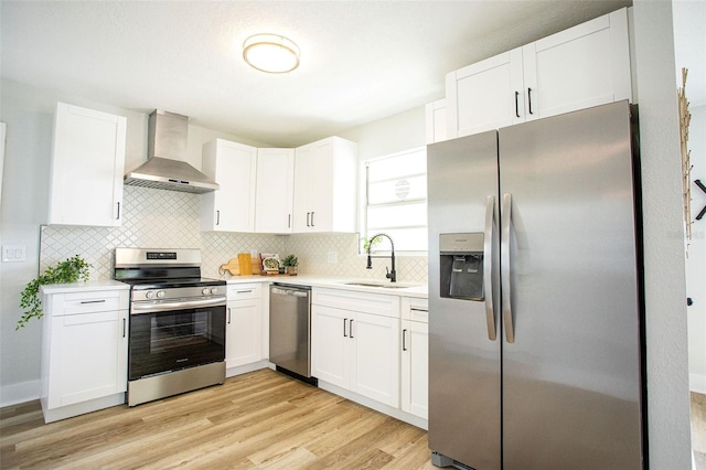 kitchen with light countertops, decorative backsplash, appliances with stainless steel finishes, a sink, and wall chimney range hood