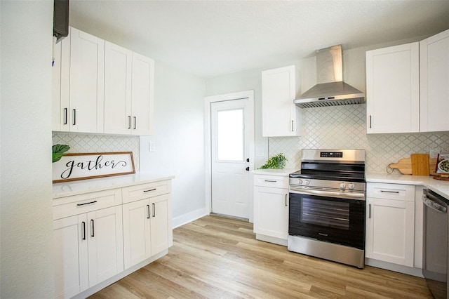 kitchen featuring light wood finished floors, light countertops, appliances with stainless steel finishes, white cabinets, and wall chimney exhaust hood