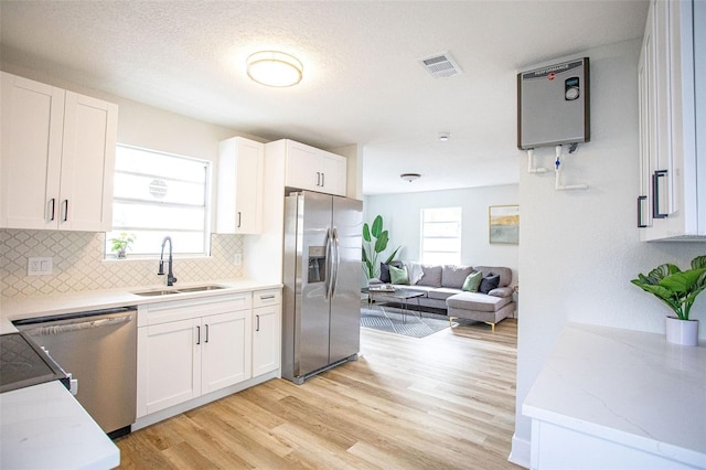 kitchen with stainless steel appliances, a sink, visible vents, white cabinets, and light wood-type flooring