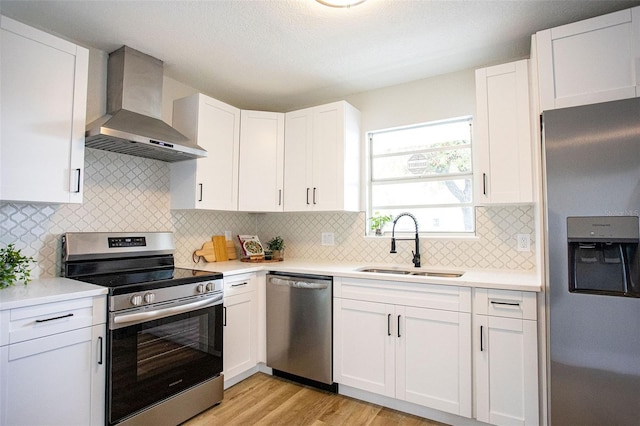 kitchen featuring wall chimney exhaust hood, stainless steel appliances, a sink, and light countertops