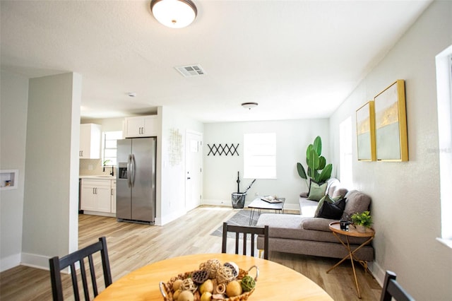 dining room with visible vents, light wood-style flooring, and baseboards