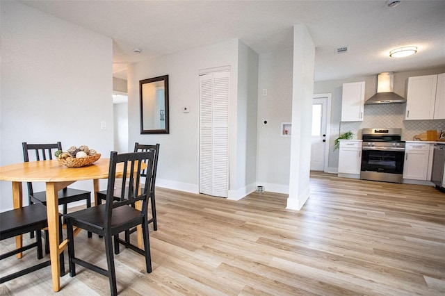 dining space with light wood finished floors, baseboards, and visible vents