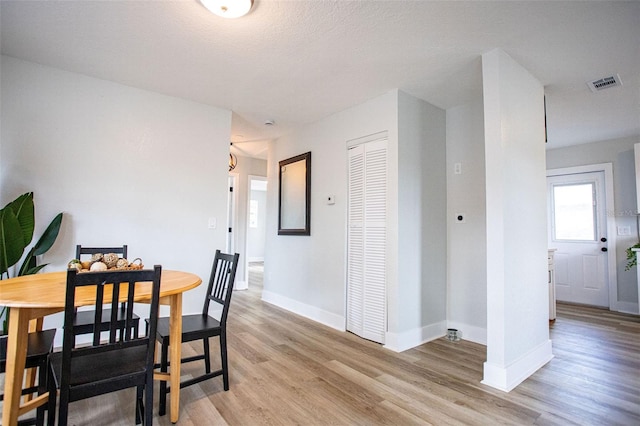 dining space featuring light wood-type flooring, visible vents, and baseboards