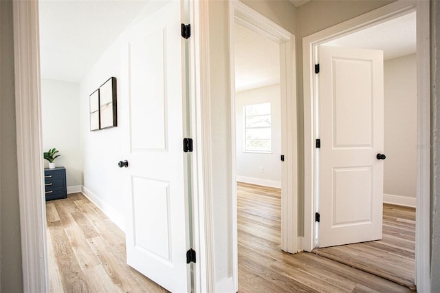 hall with light wood finished floors and baseboards