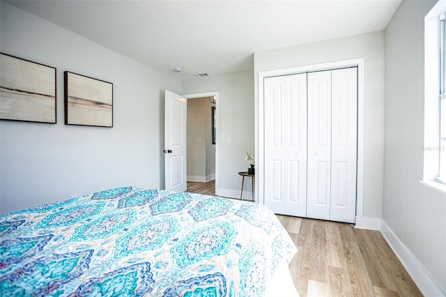 bedroom featuring visible vents, a closet, light wood-style flooring, and baseboards