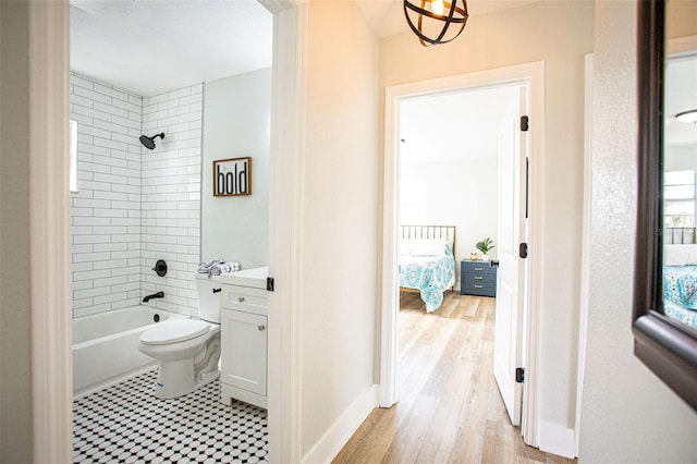 ensuite bathroom with toilet, wood finished floors, baseboards, ensuite bath, and washtub / shower combination