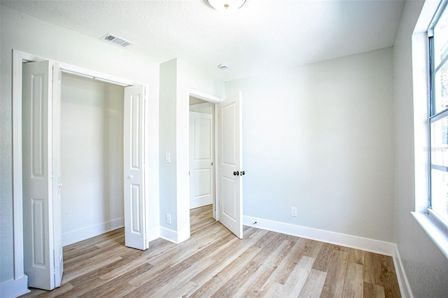 unfurnished bedroom featuring multiple windows, wood finished floors, and baseboards