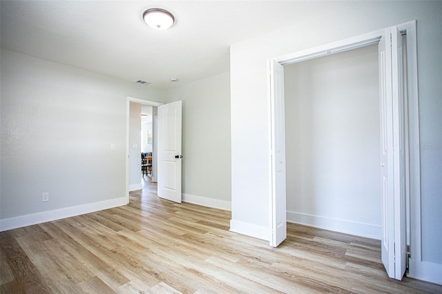 unfurnished bedroom with light wood-style floors, visible vents, baseboards, and a closet