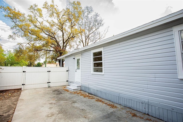 view of home's exterior featuring entry steps, a gate, a patio area, and fence