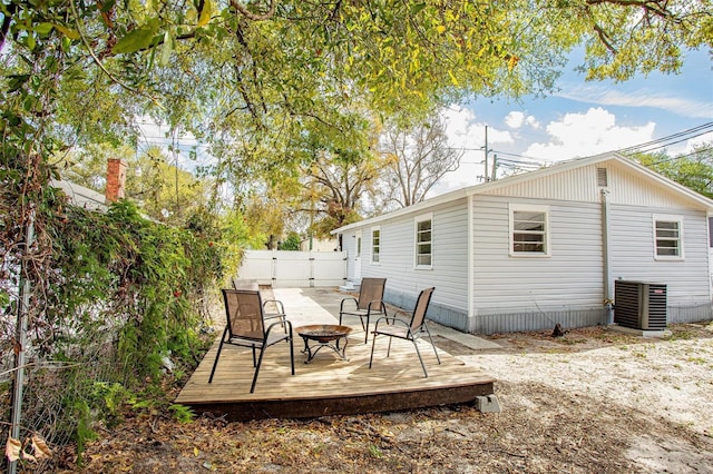 rear view of property featuring an outdoor fire pit, a gate, fence, and cooling unit