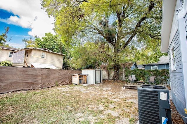 view of yard featuring a storage shed, a fenced backyard, cooling unit, and an outdoor structure