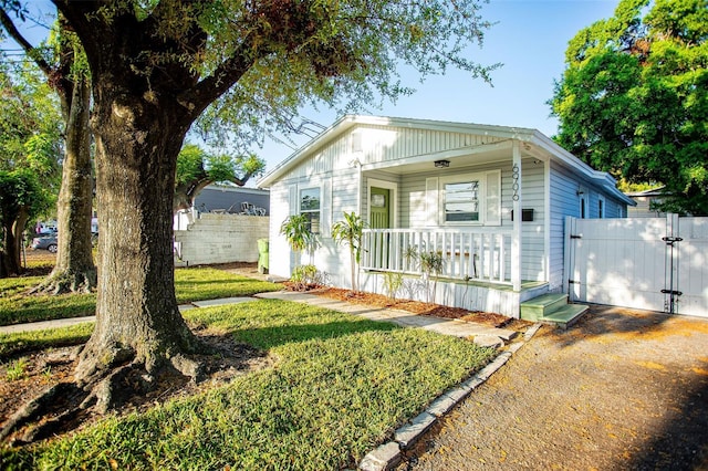 view of front of home with dirt driveway, fence, covered porch, a garage, and a gate