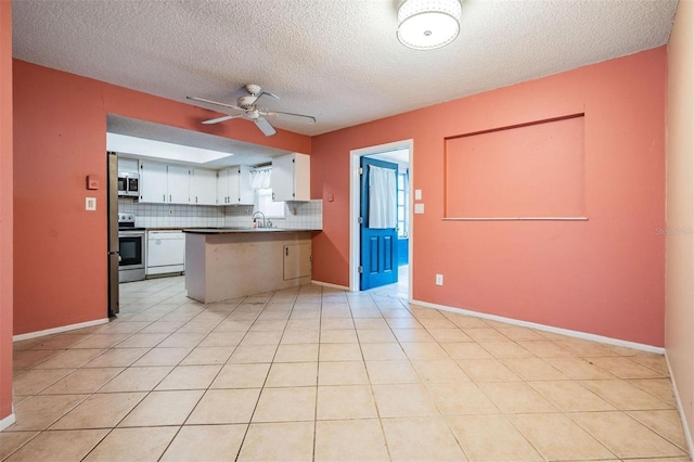 kitchen featuring ceiling fan, a peninsula, white cabinets, appliances with stainless steel finishes, and decorative backsplash