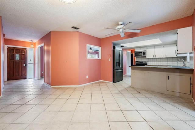 kitchen with visible vents, a ceiling fan, appliances with stainless steel finishes, a peninsula, and backsplash