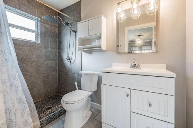 full bath featuring toilet, vanity, baseboards, a tile shower, and tile patterned floors