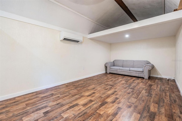 sitting room with an AC wall unit, vaulted ceiling with beams, baseboards, and wood finished floors