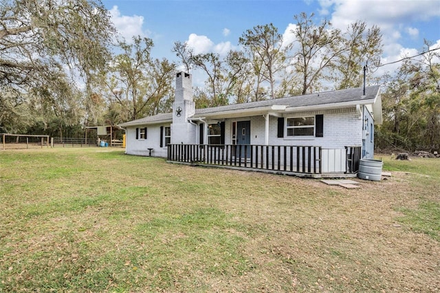 back of house featuring a chimney, fence, a lawn, and brick siding