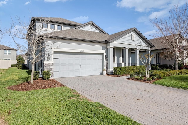 view of front of house with decorative driveway, stucco siding, a shingled roof, a front yard, and a garage