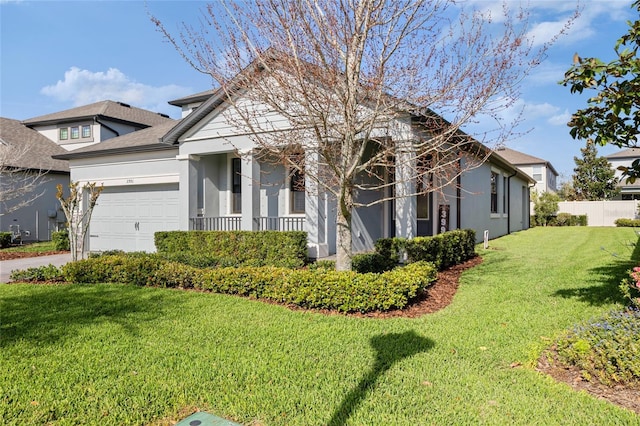 view of front of home with a garage, fence, a front lawn, and stucco siding