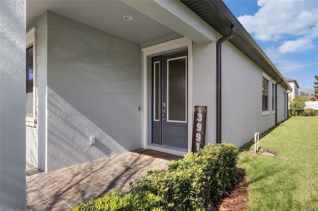 view of exterior entry featuring a yard and stucco siding