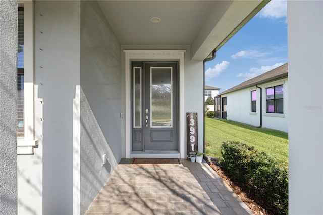 property entrance featuring a yard and stucco siding