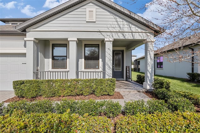 view of front of house featuring an attached garage, covered porch, and stucco siding