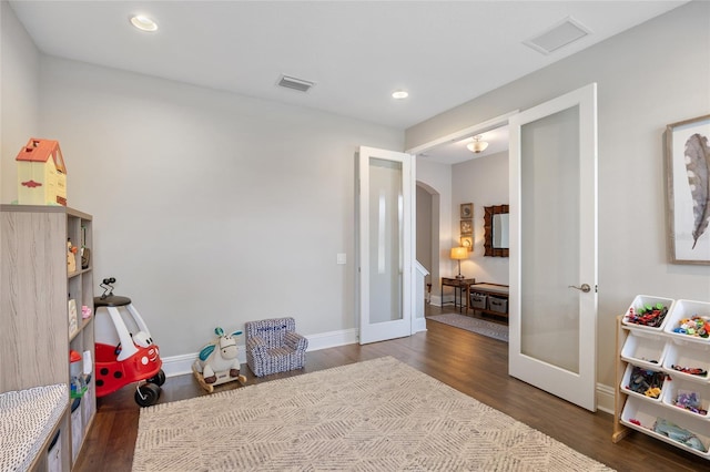 recreation room featuring visible vents, arched walkways, wood finished floors, and french doors