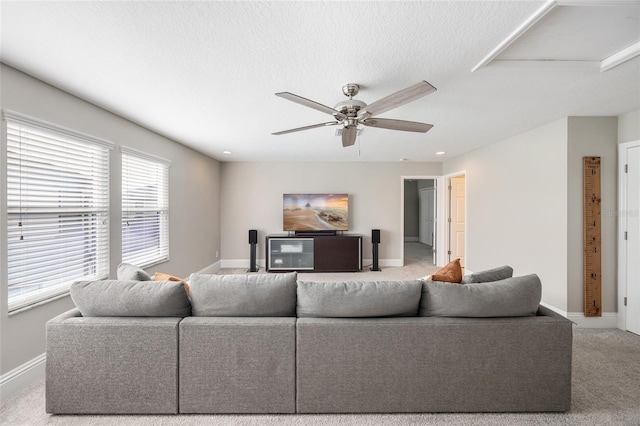 living area featuring a ceiling fan, carpet, a textured ceiling, and baseboards