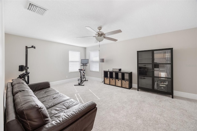 carpeted living area with a ceiling fan, visible vents, a textured ceiling, and baseboards