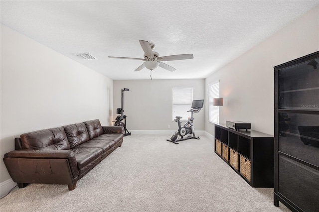 carpeted living area with a ceiling fan, visible vents, a textured ceiling, and baseboards