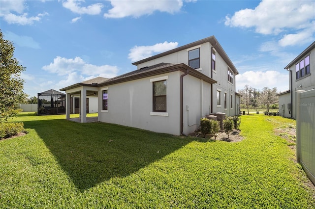rear view of house featuring a lawn and stucco siding
