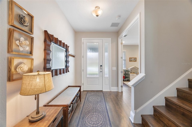 entryway with visible vents, baseboards, dark wood finished floors, and stairs