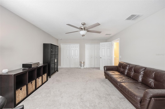 living area featuring visible vents, baseboards, ceiling fan, and light carpet