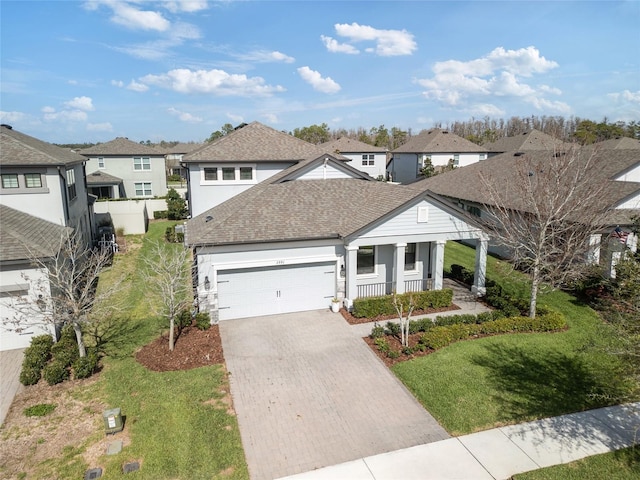 single story home featuring a residential view, roof with shingles, an attached garage, a porch, and decorative driveway