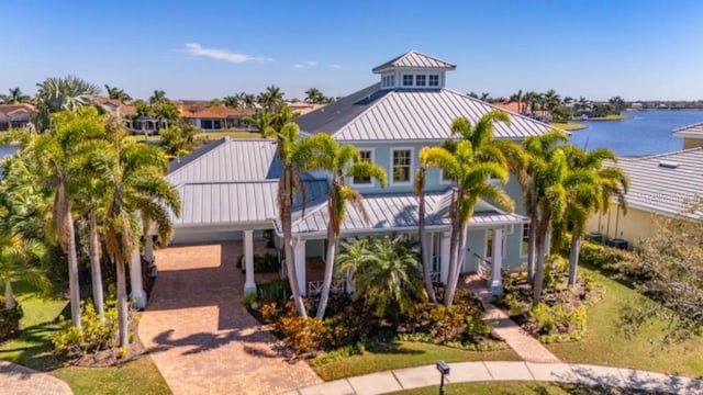 view of front facade with a water view, a standing seam roof, metal roof, and decorative driveway